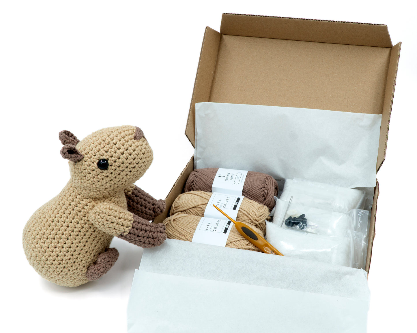 amigurumi crochet capybara kit with capybara sitting next to a box of yarn