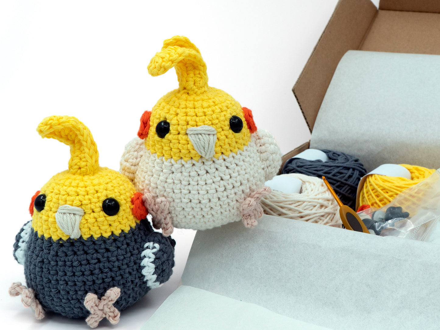 amigurumi crochet cockatiel kit grey and lutino parrots sitting next to a box of yarn