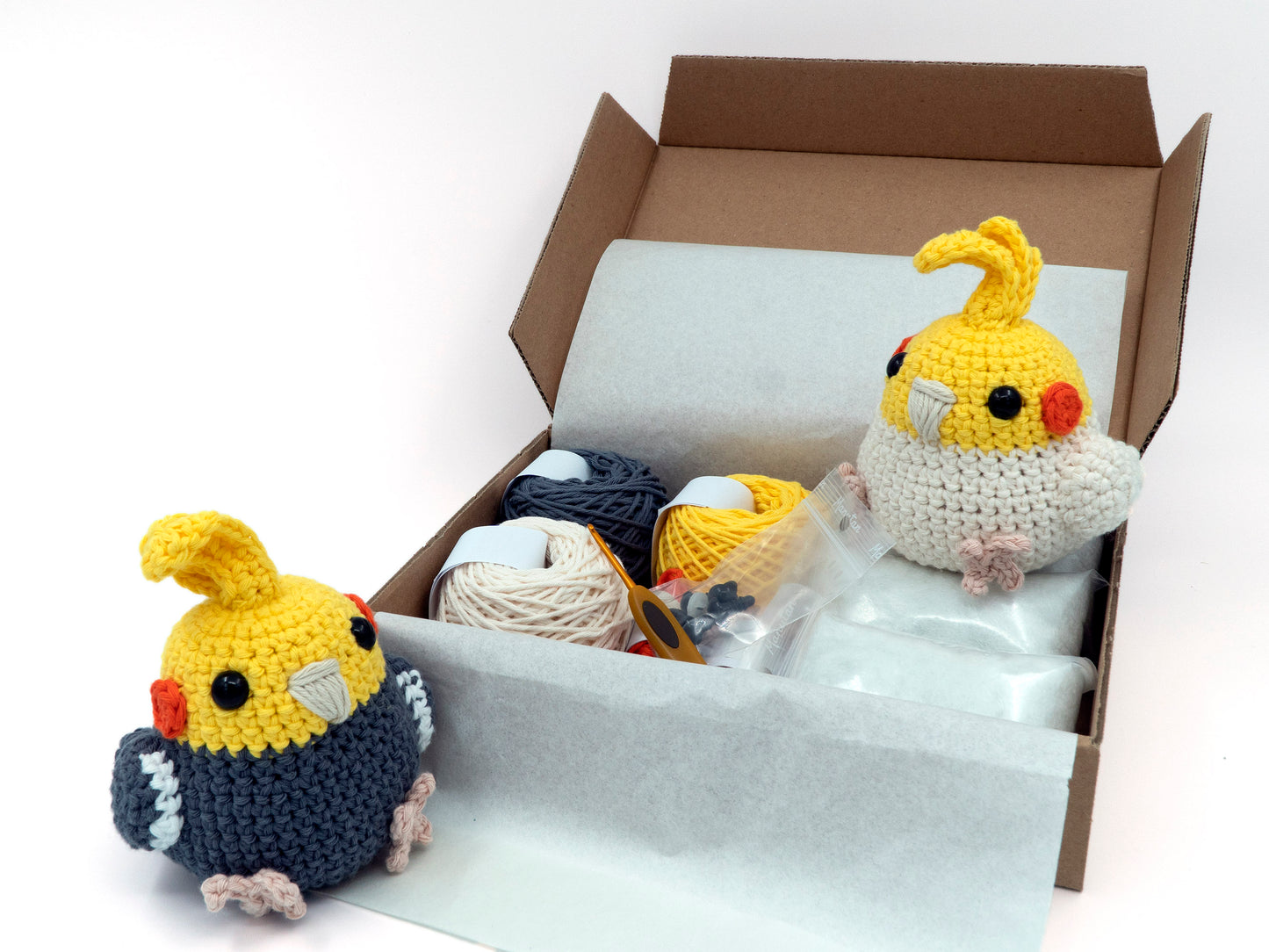 amigurumi crochet cockatiel kit grey and lutino parrots sitting inside a box of yarn