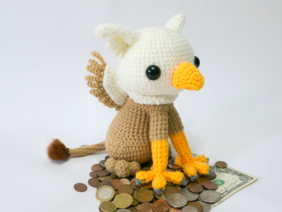 amigurumi crochet griffin pattern sitting on a pile of money