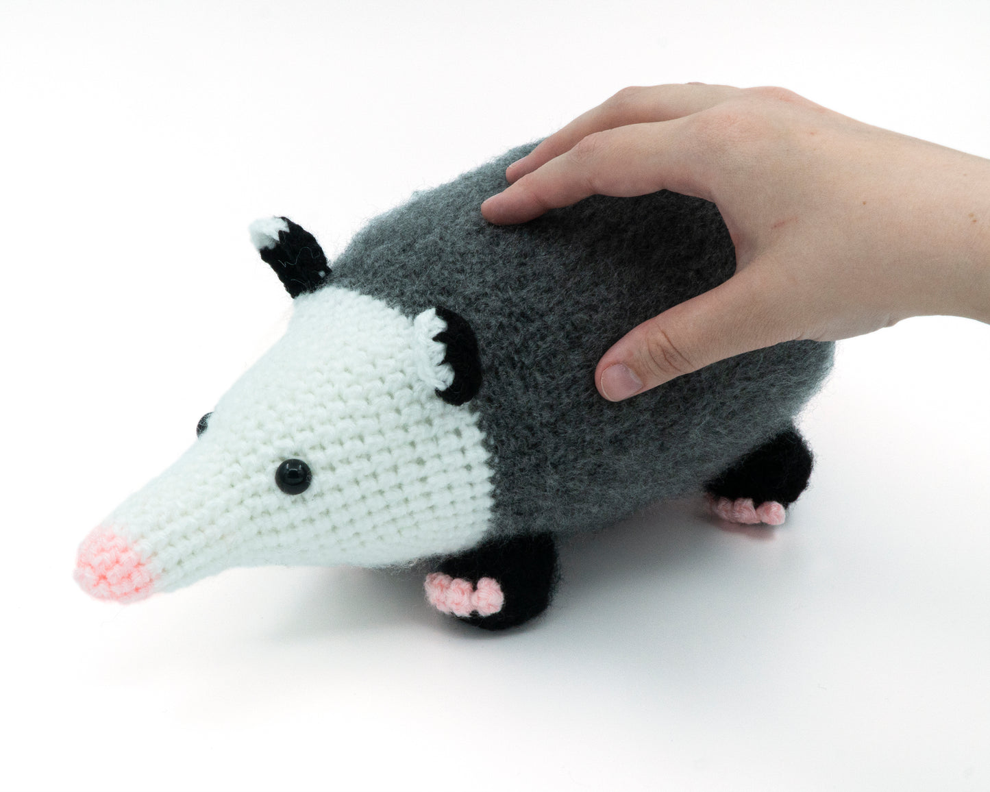 amigurumi crochet opossum pattern in hand for size comparison