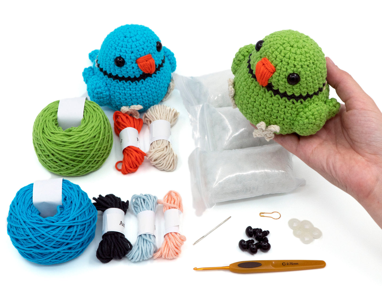 amigurumi crochet indian ringneck kit bird being held above the contents of the crochet kit