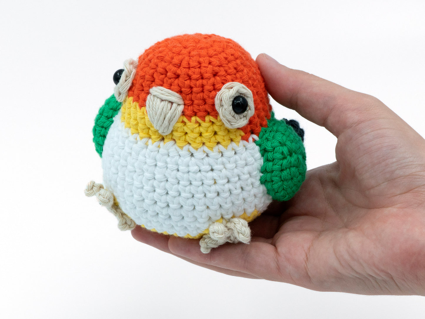 amigurumi crochet caique pattern parrot sitting in hand for size comparison