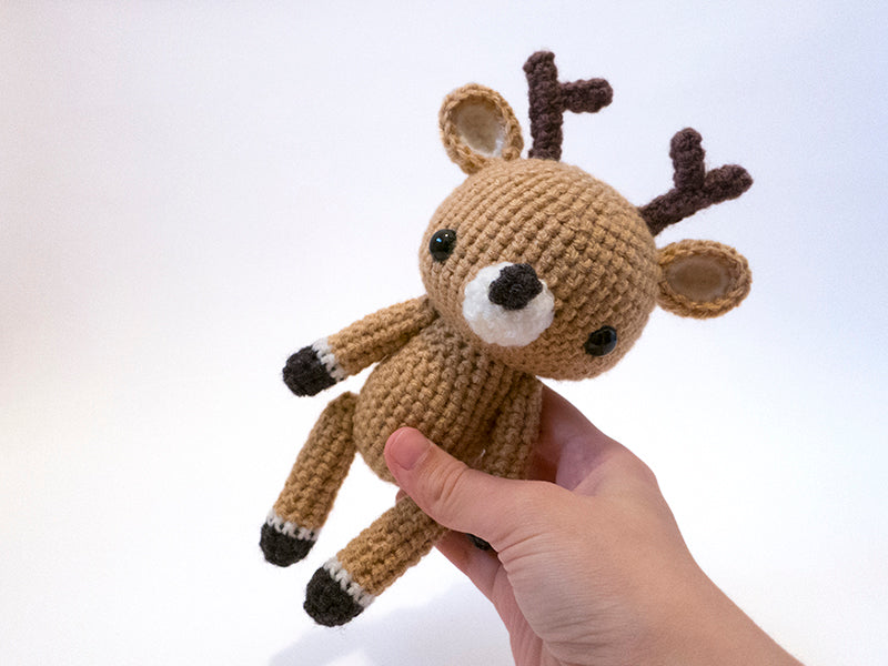 amigurumi crochet deer pattern in hand for size comparison