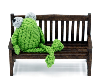 amigurumi crochet sitting frog pattern sitting in on a bench with crossed legs