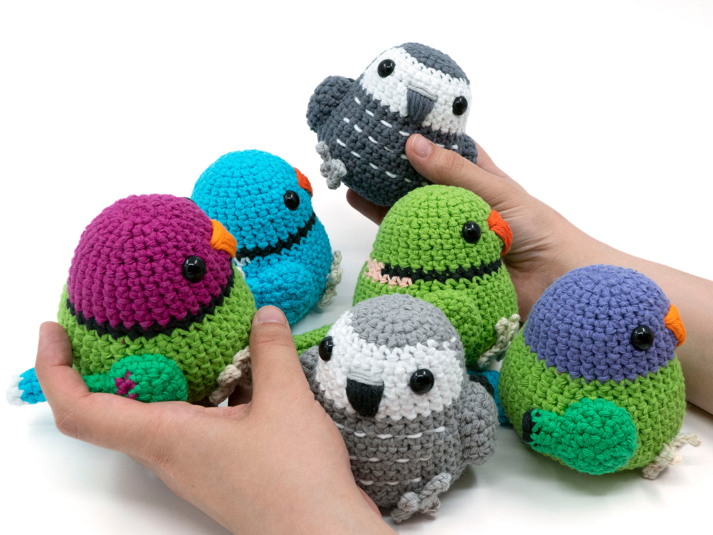 amigurumi crochet parrot pattern bundle with african grey plum-headed parakeet and indian ringneck being held for size comparison