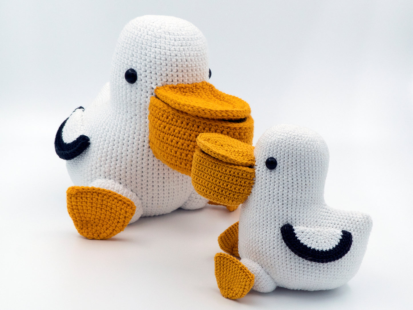 two amigurumi pelicans with yellow beaks and feet