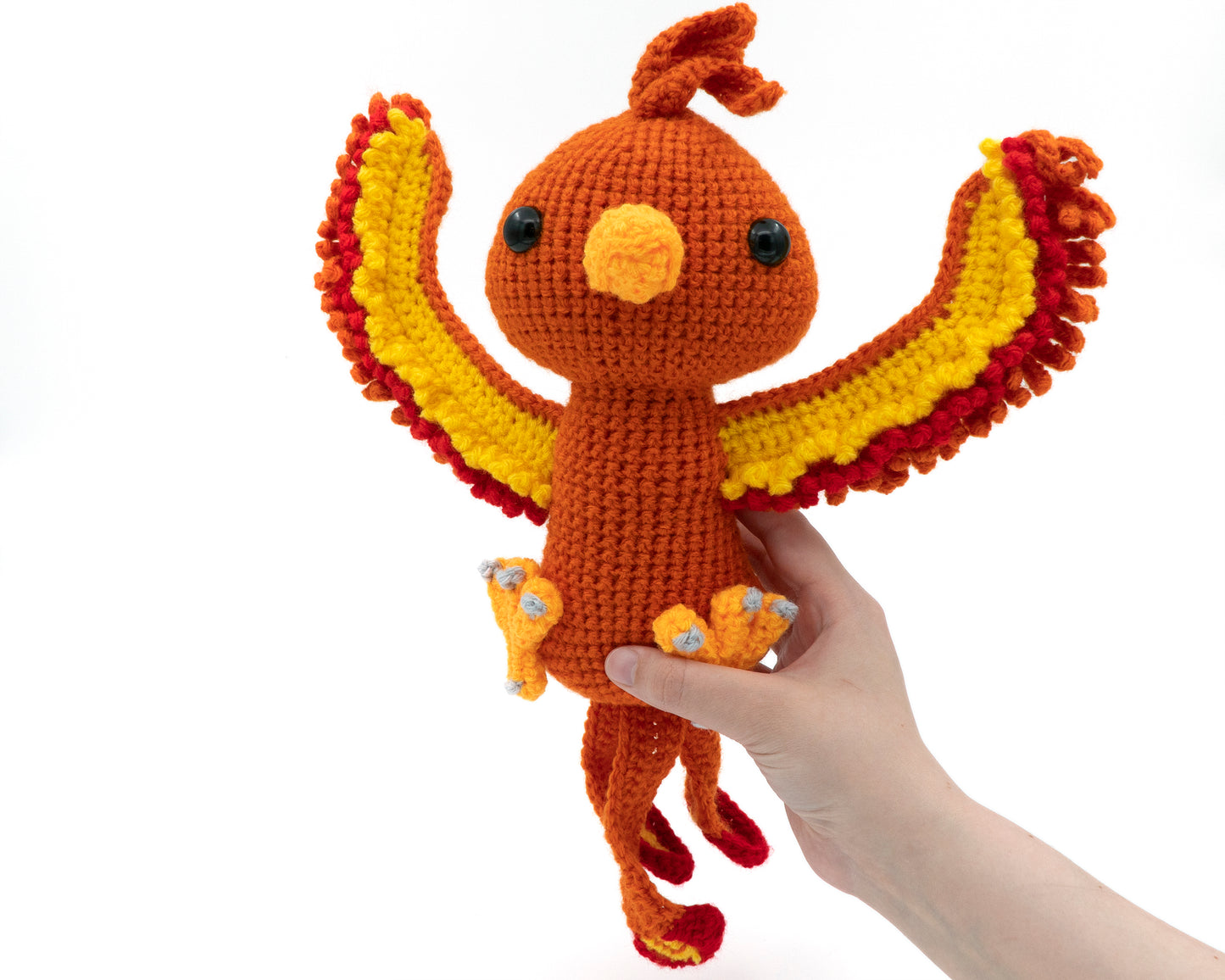 amigurumi crochet phoenix pattern in hand for size comparison