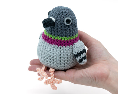 amigurumi crochet pigeon pattern sitting in the palm of a hand for size comparison