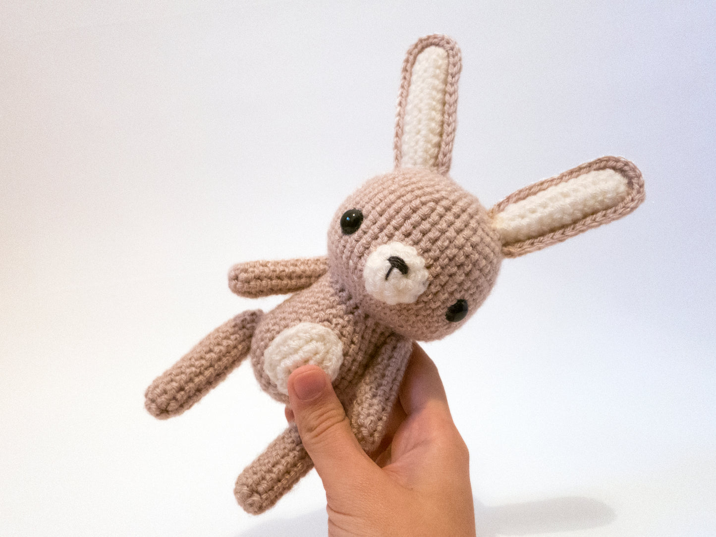 amigurumi crochet rabbit pattern in hand for size comparison