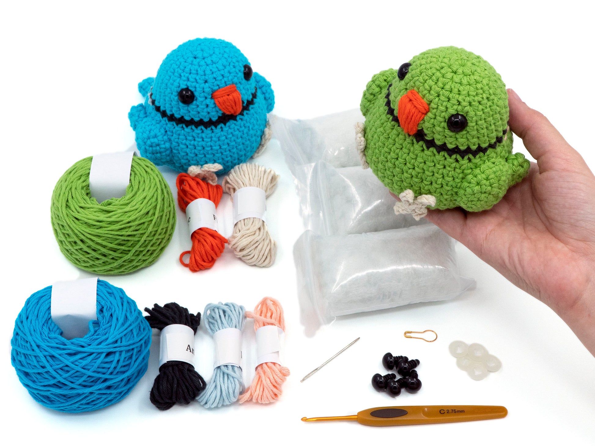 amigurumi crochet indian ringneck kit bird being held above the contents of the crochet kit