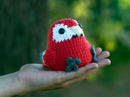 handmade crochet scarlet macaw amigurumi plush sitting in hand outside for size comparison