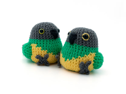 Two crocheted parrot toys in green, yellow, and gray on a white background