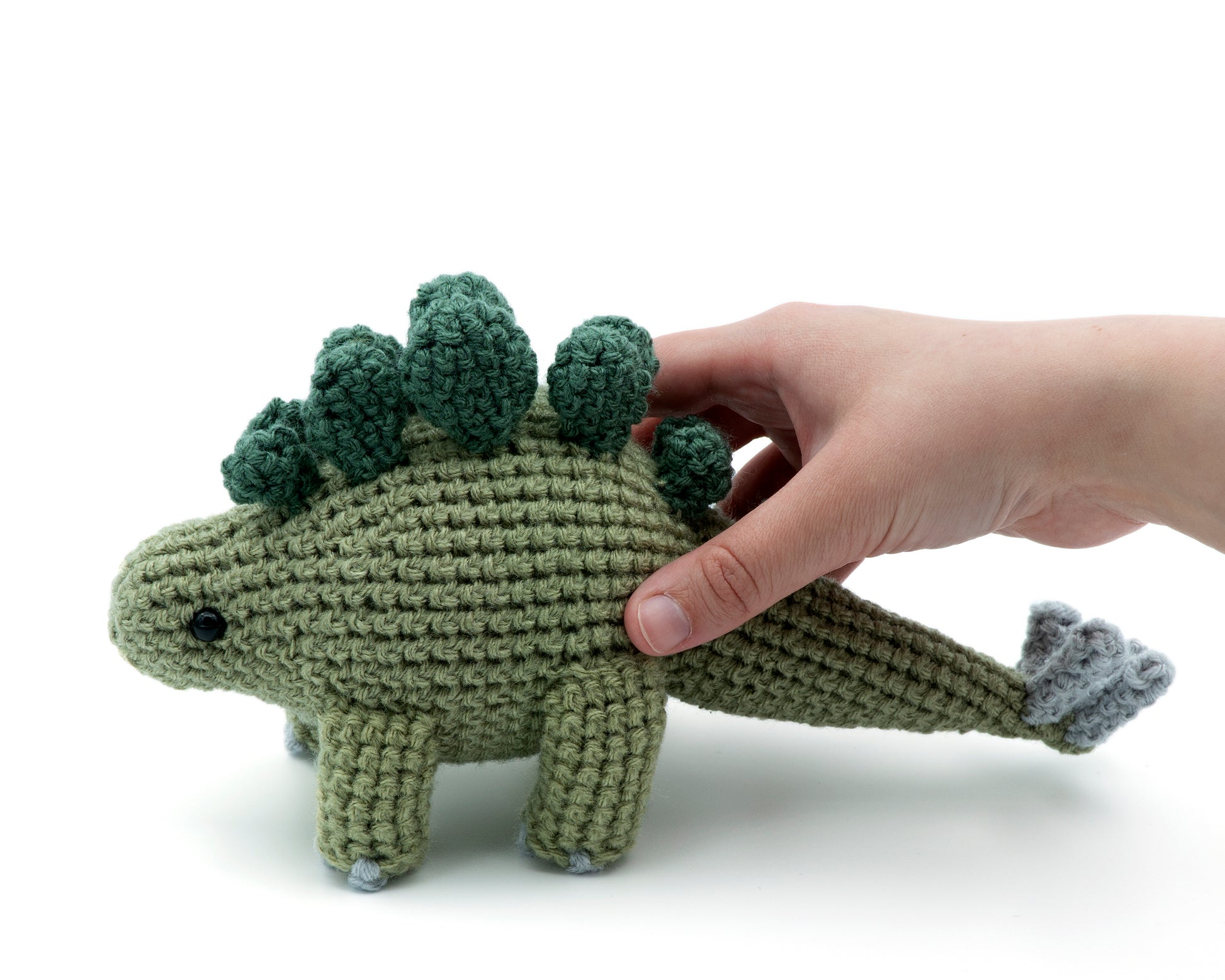 amigurumi crochet stegosaurus pattern in hand for size comparison