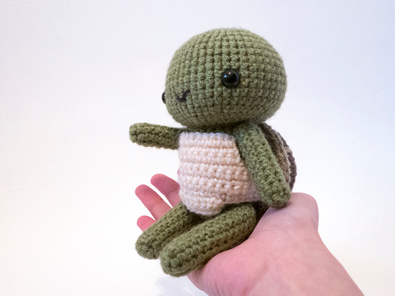 amigurumi crochet turtle pattern in hand for size comparison