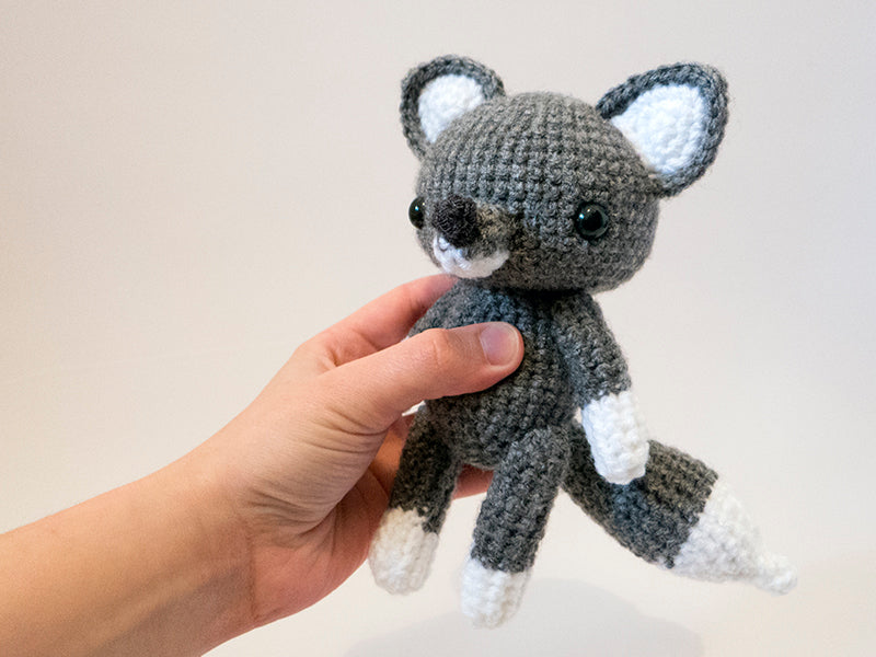 amigurumi crochet wolf pattern in hand for size comparison